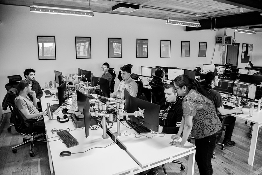 Grey photo of a group of employees working on their computers.