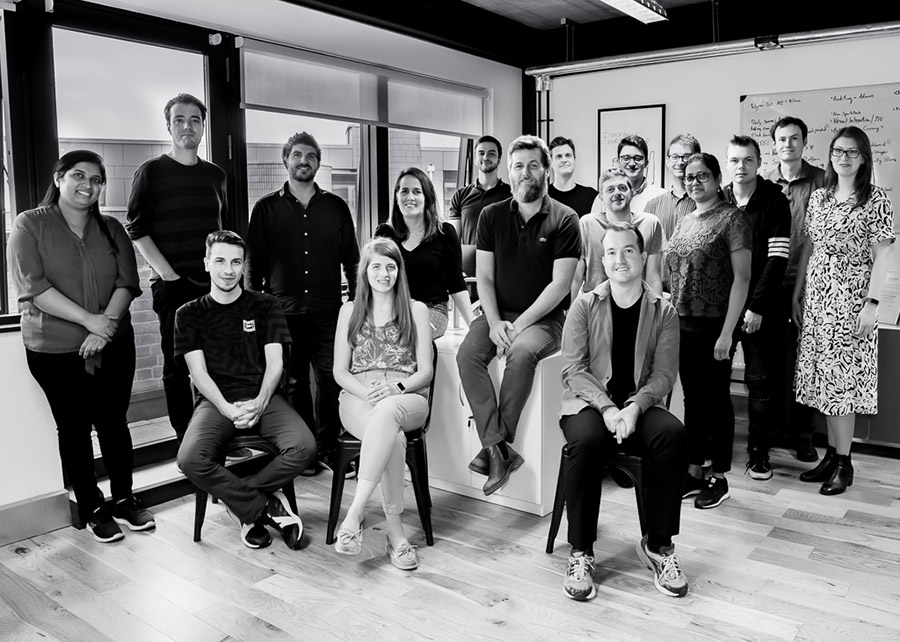 Grey photo of employees looking into a camera.